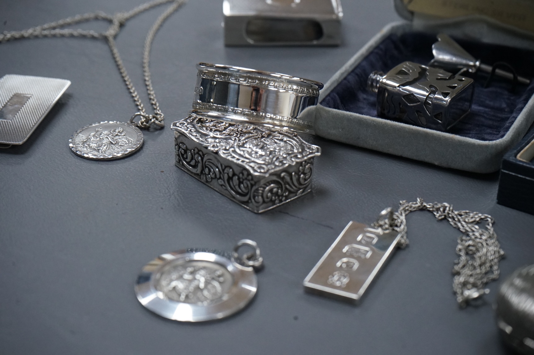 A group of mainly modern silver collectables including three assorted scent flasks and funnels by Ari D. Norman, two money clips, matchbox sleeve, napkin ring, pill box, three pendants including ingot and a pair of Victo